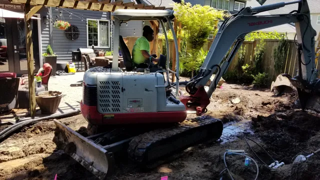 Mini excavator digging in a backyard patio renovation