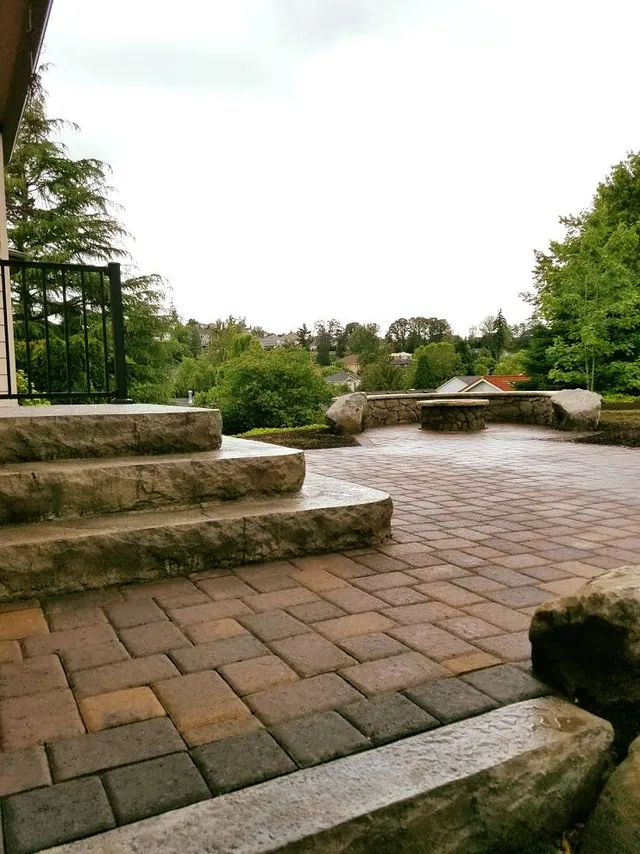Paver patio with chiseled stone steps and a boulder-edged stone bench overlook