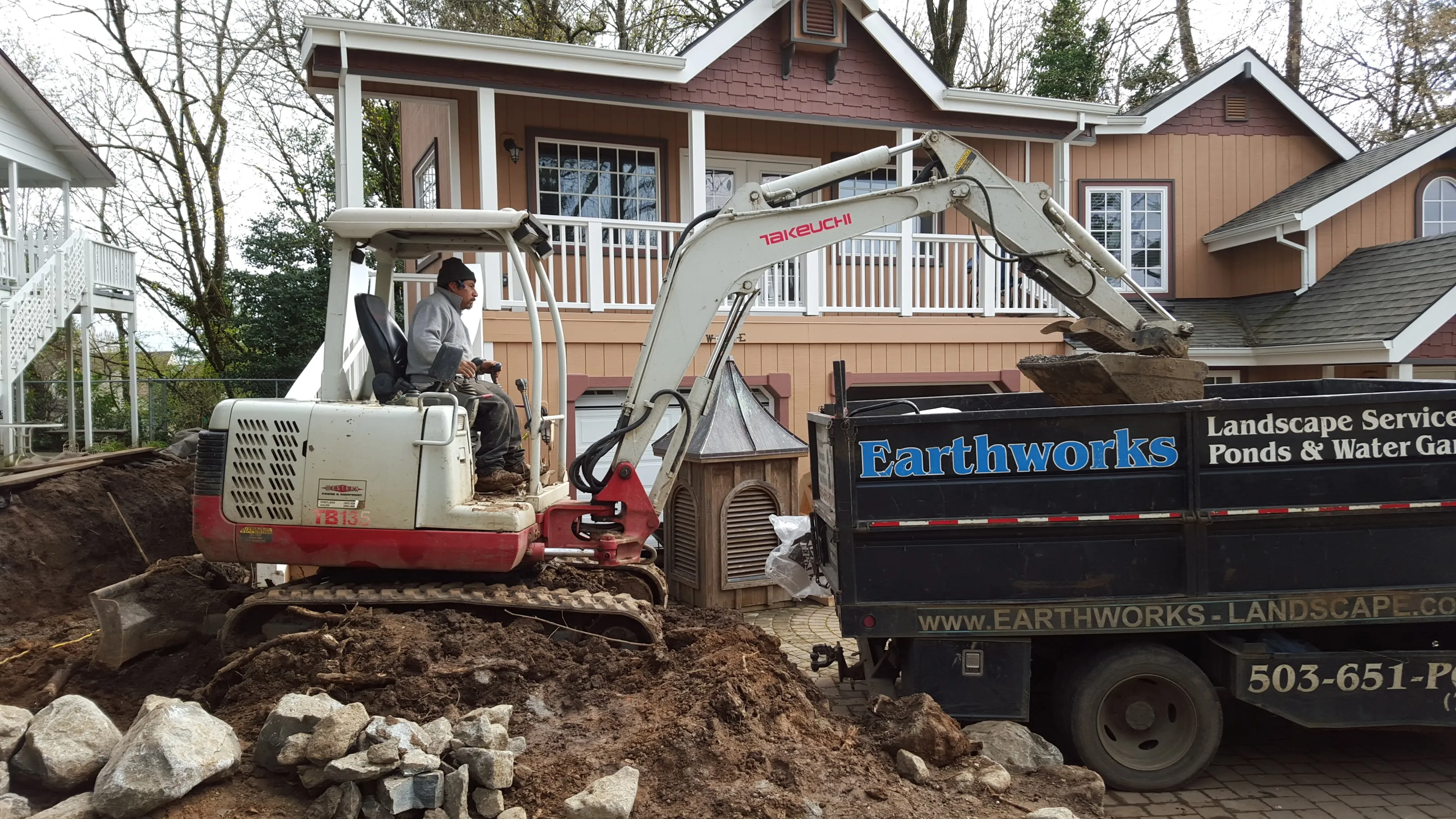 Earthworks track hoe loading the company dump truck on an excavation job
