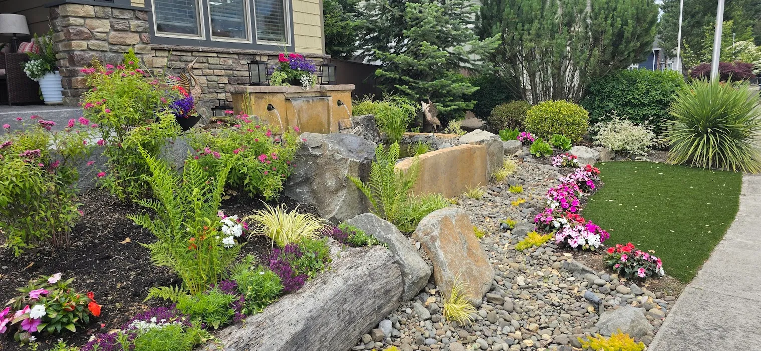 Finished custom water wall with dry creek, boulders, and flowering beds