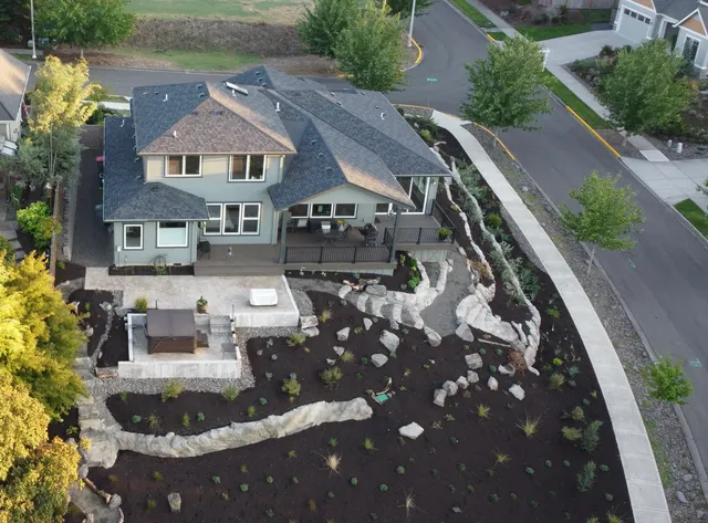 Aerial view of a completed new-construction landscape with carved-rock walls and fresh plantings