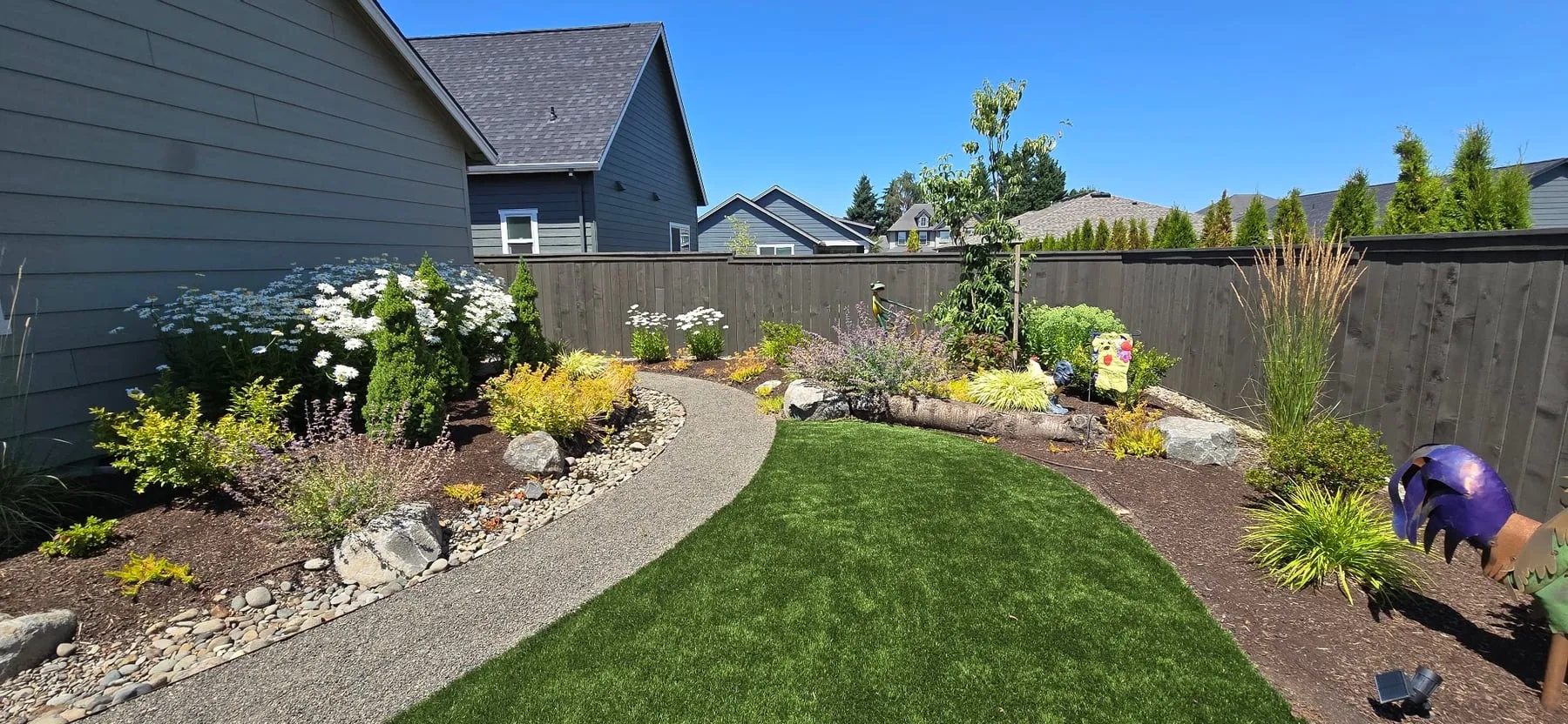 Canby backyard with a curved gravel path, fresh lawn, and newly planted beds along a cedar fence