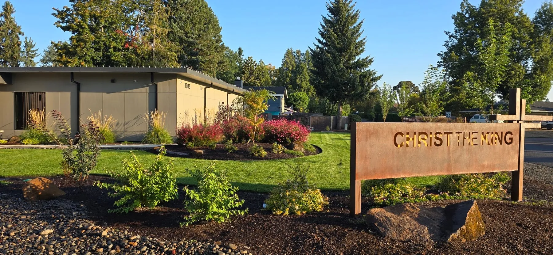 Fresh plantings, bark beds, and a clean lawn edge beside a church sign at a Canby campus