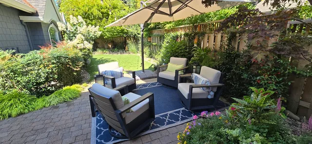 Paver patio outdoor living room with cantilever umbrella, swivel chairs, and layered planting