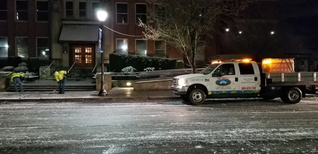Earthworks crew shoveling and de-icing a commercial entrance before opening