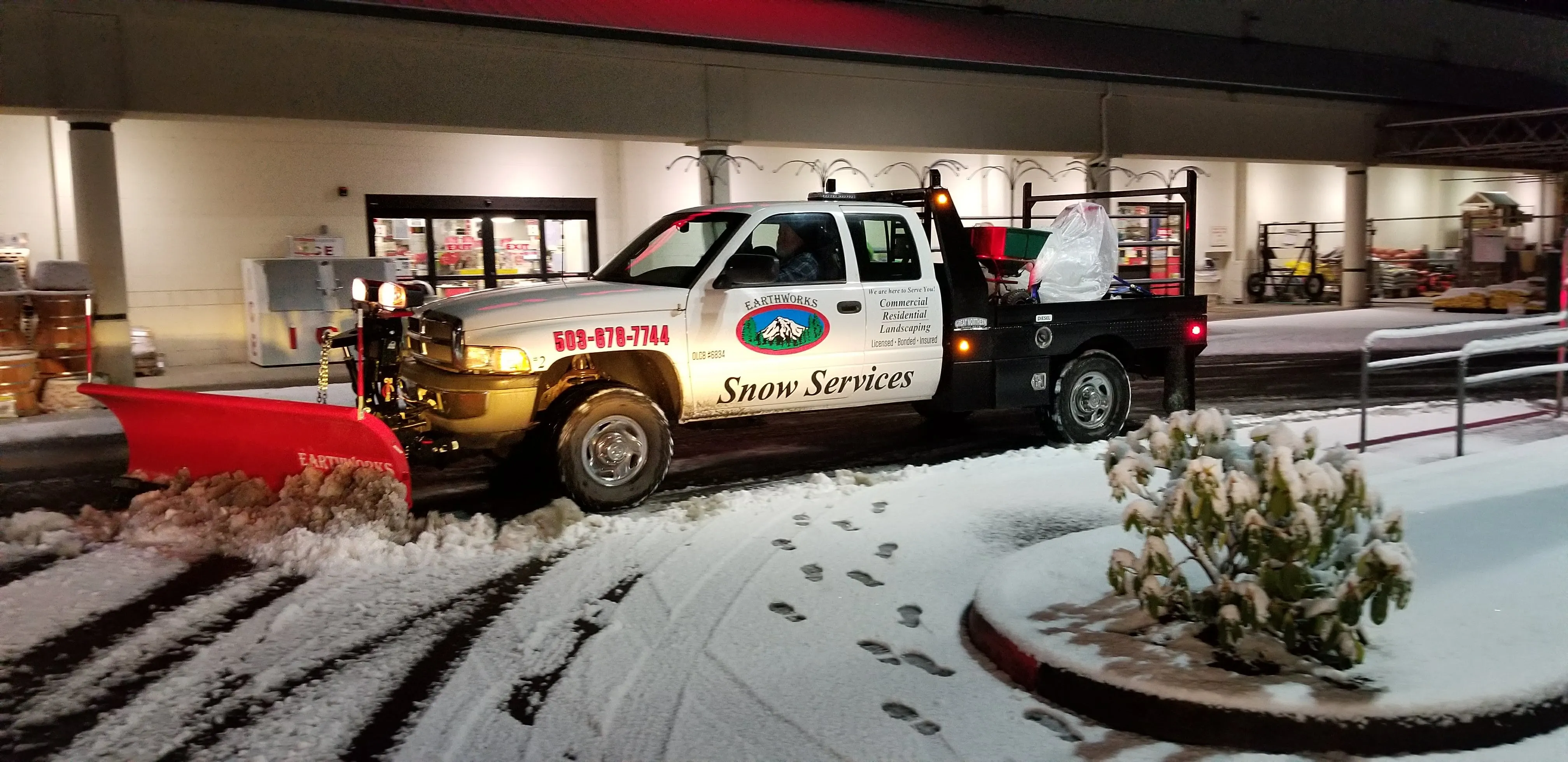 Earthworks plow truck clearing a snowy commercial lot overnight