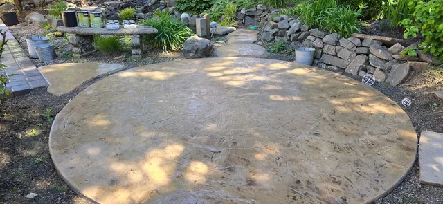 Stamped concrete patio with an impressed circular medallion, edged in stacked stone