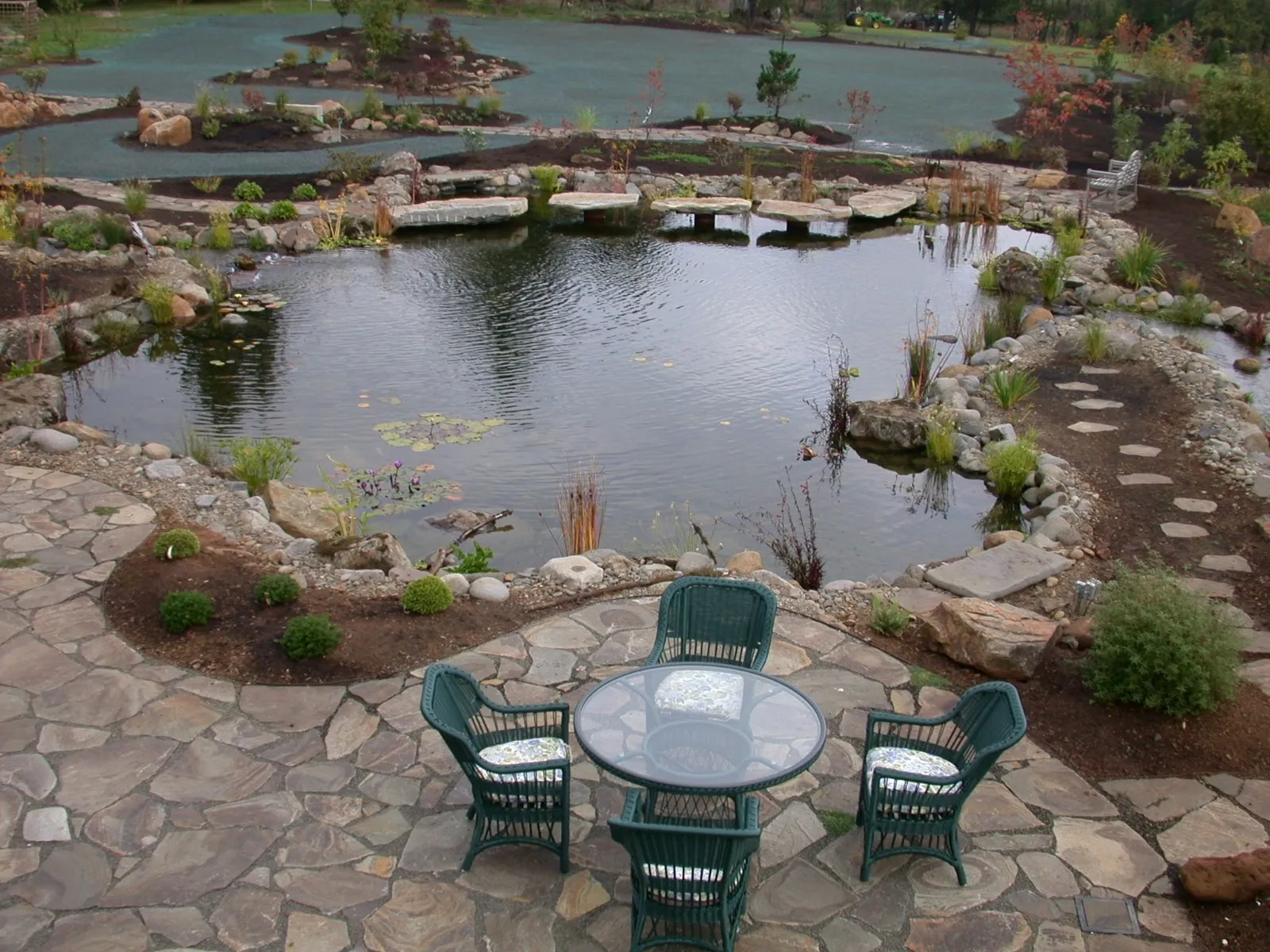 Flagstone terrace overlooking a large natural pond with stone slab crossings at an Oregon City estate